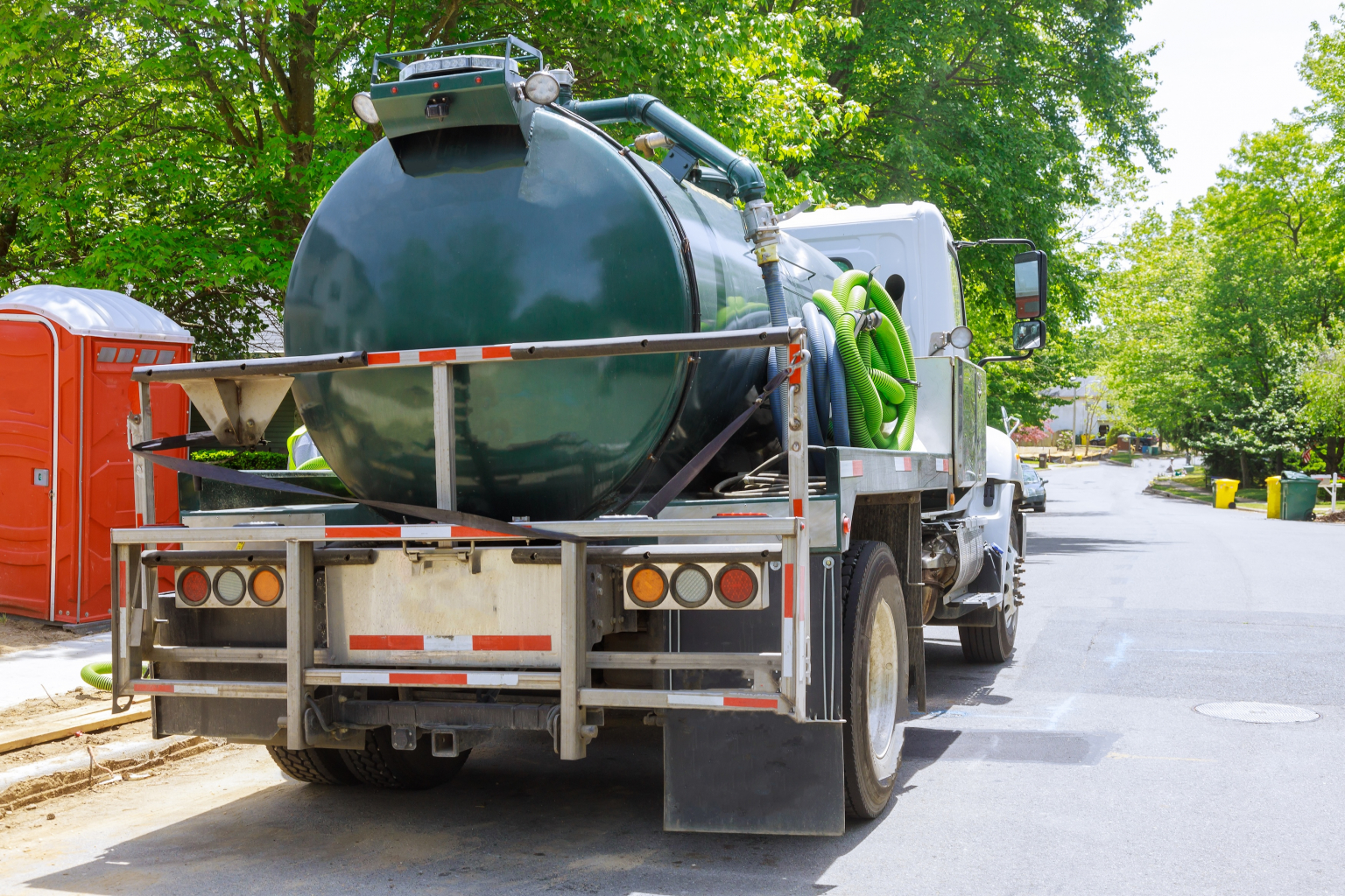 Vacuum waste truck on the cleaning process portable bio toilet cabins in the construction